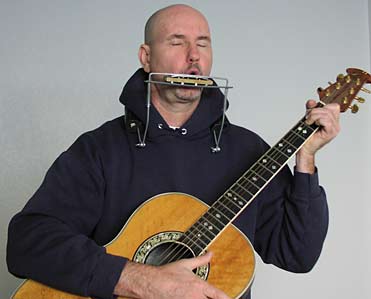Guitar with harmonica on neck rack